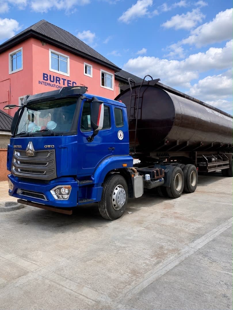 Line of clean white and brown commercial fuel delivery trucks parked in order